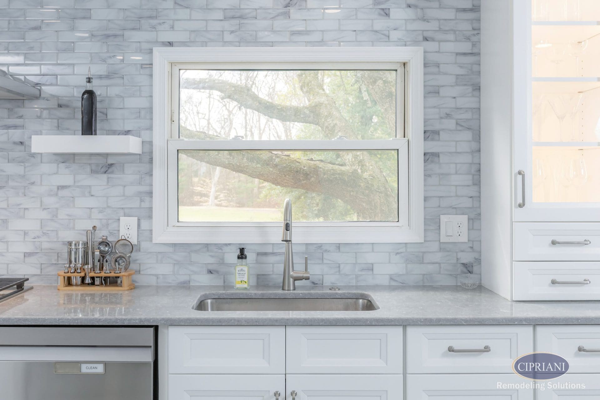 Kitchen sink under large window with marble backsplash