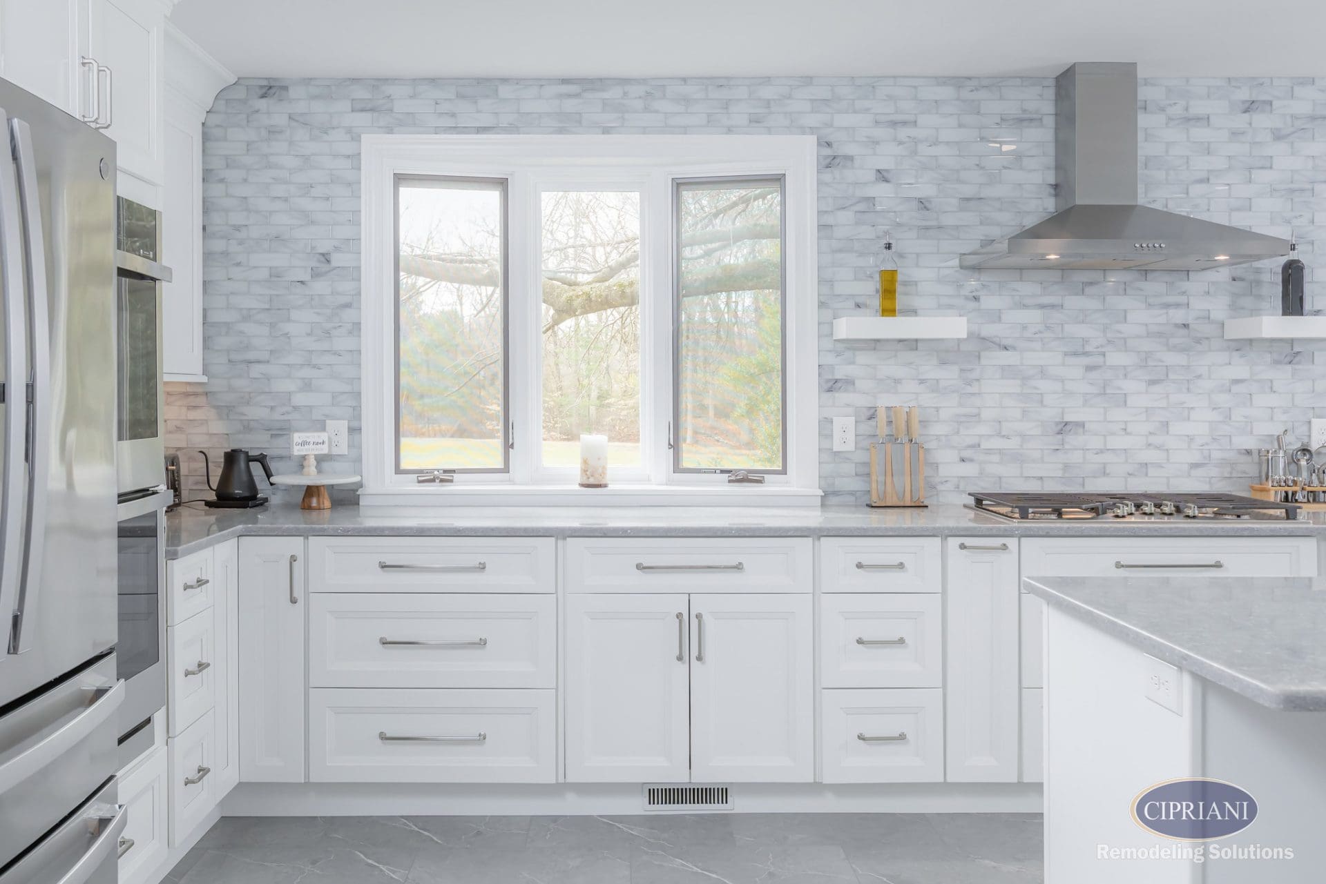 White cabinetry and stainless accents in a bright, airy kitchen with large window