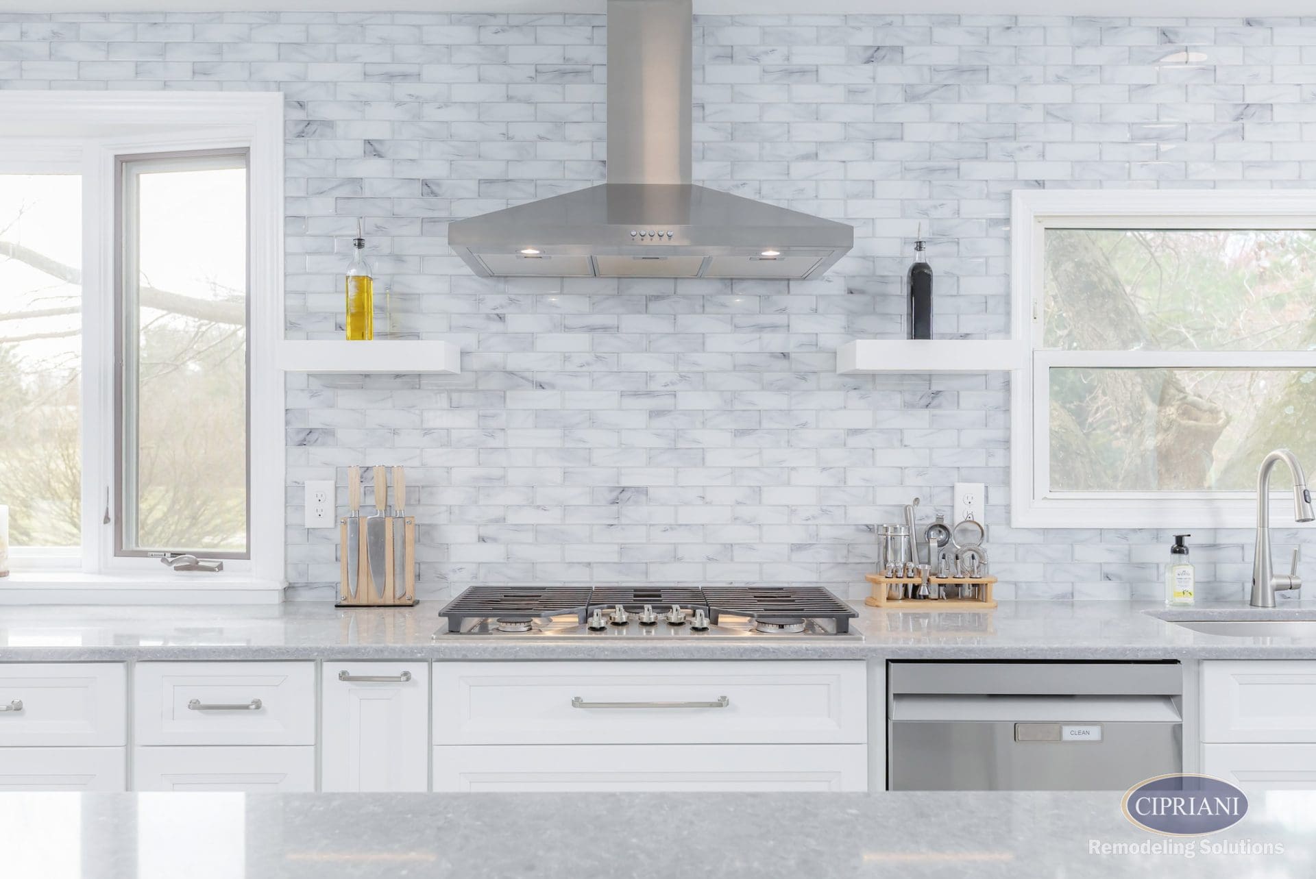 Stainless steel range hood and cooktop with white backsplash and built-in shelves