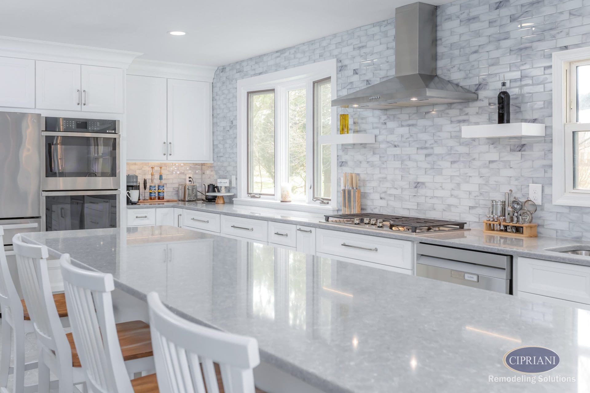 Long white kitchen island with polished gray countertops and full-height backsplash