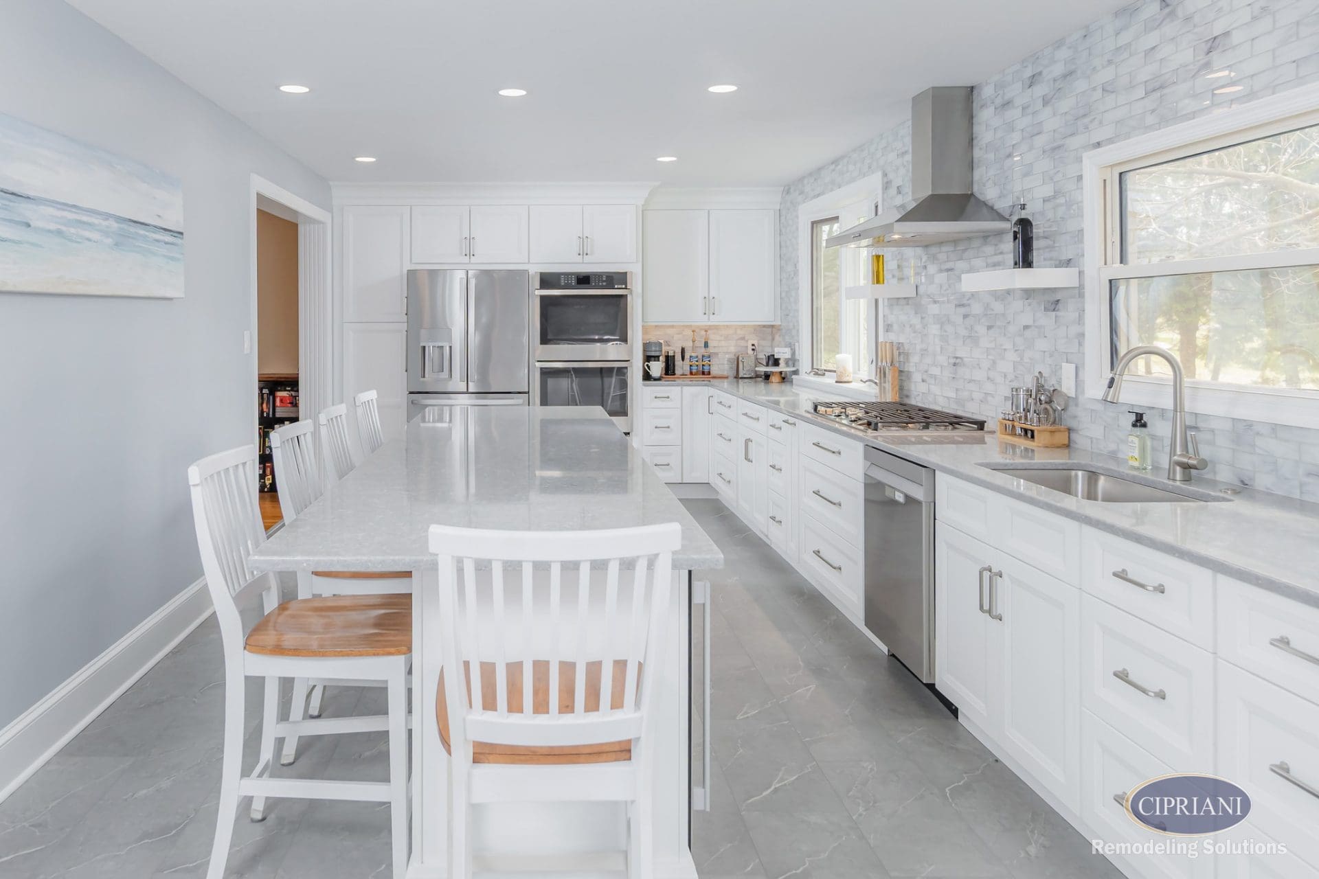 Full kitchen view with long island, white cabinetry, and marble-style backsplash