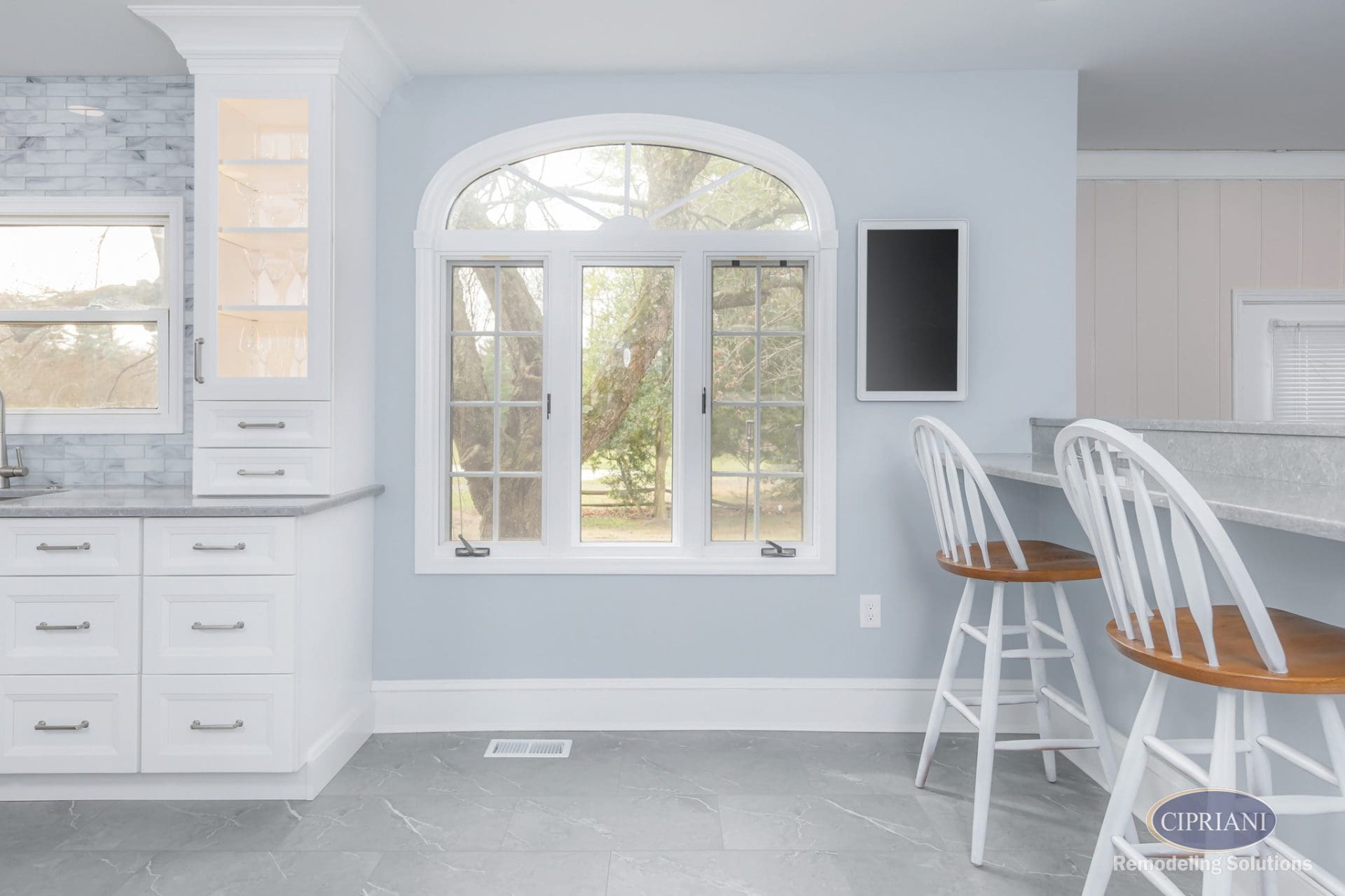 Arched window with bar seating and elegant glass cabinet in kitchen