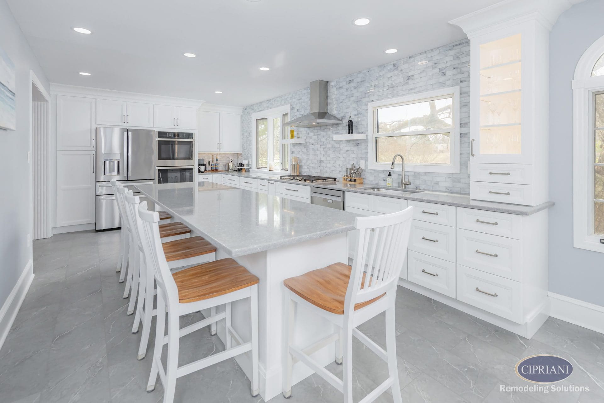 Polished kitchen island with white chairs and marble-style finishes