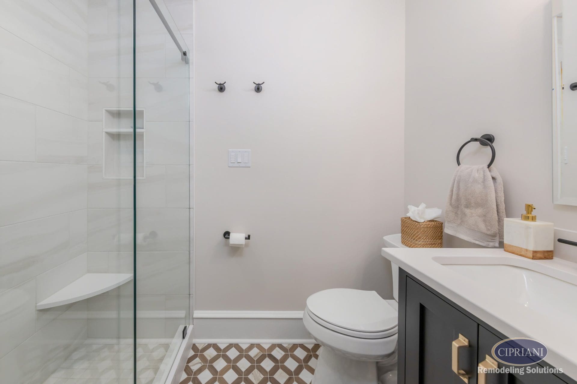 Small bathroom with glass shower, black vanity, matte black accents, and patterned tile floor.