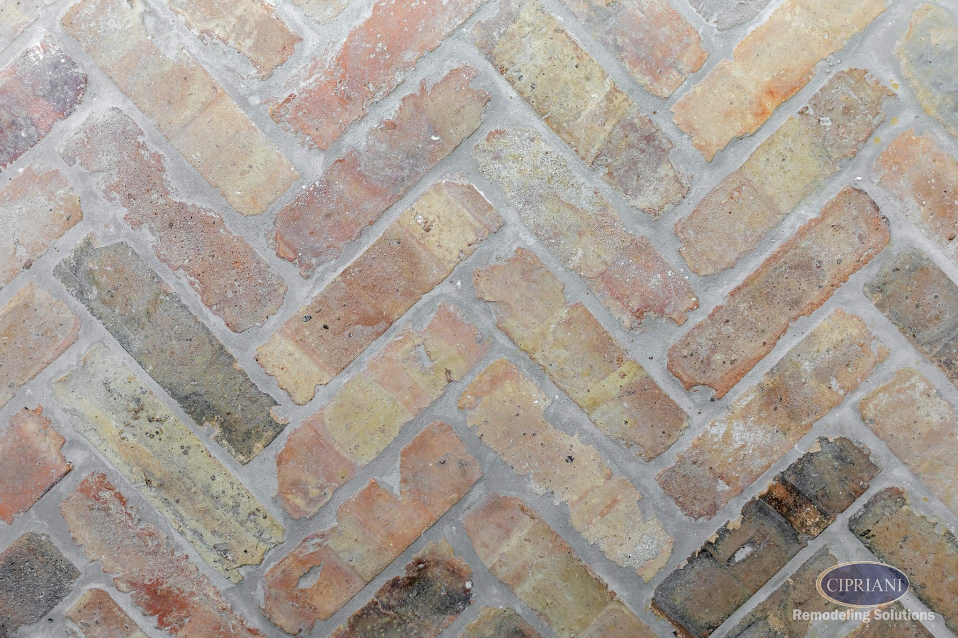 Close-up of reclaimed brick floor in a classic herringbone pattern with gray grout.
