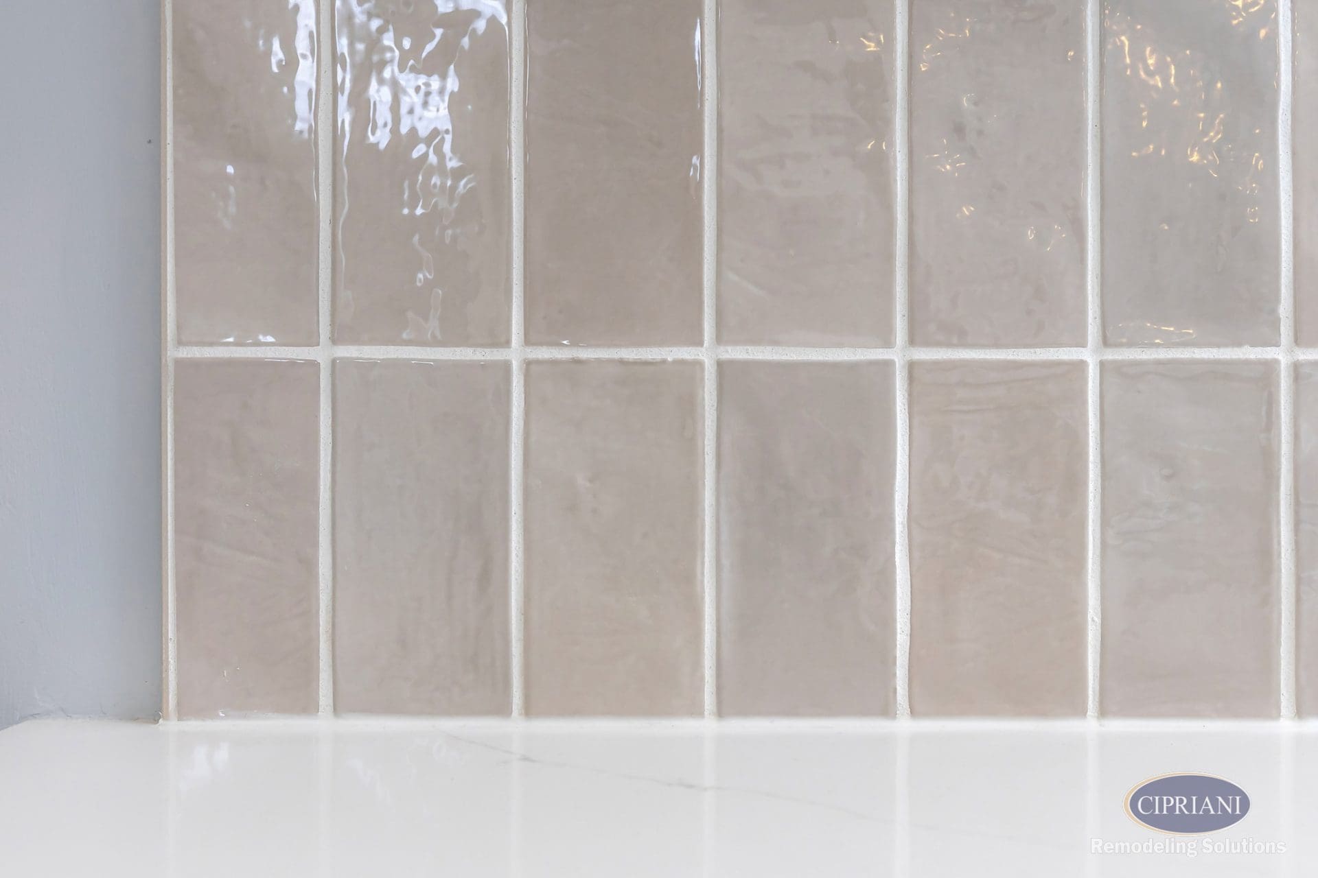 Close-up of taupe ceramic backsplash tile with glossy, hand-crafted finish.