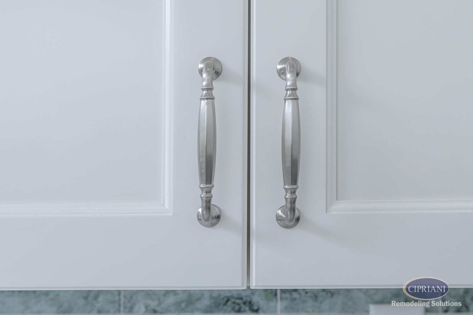 Polished nickel cabinet hardware on white shaker-style doors.