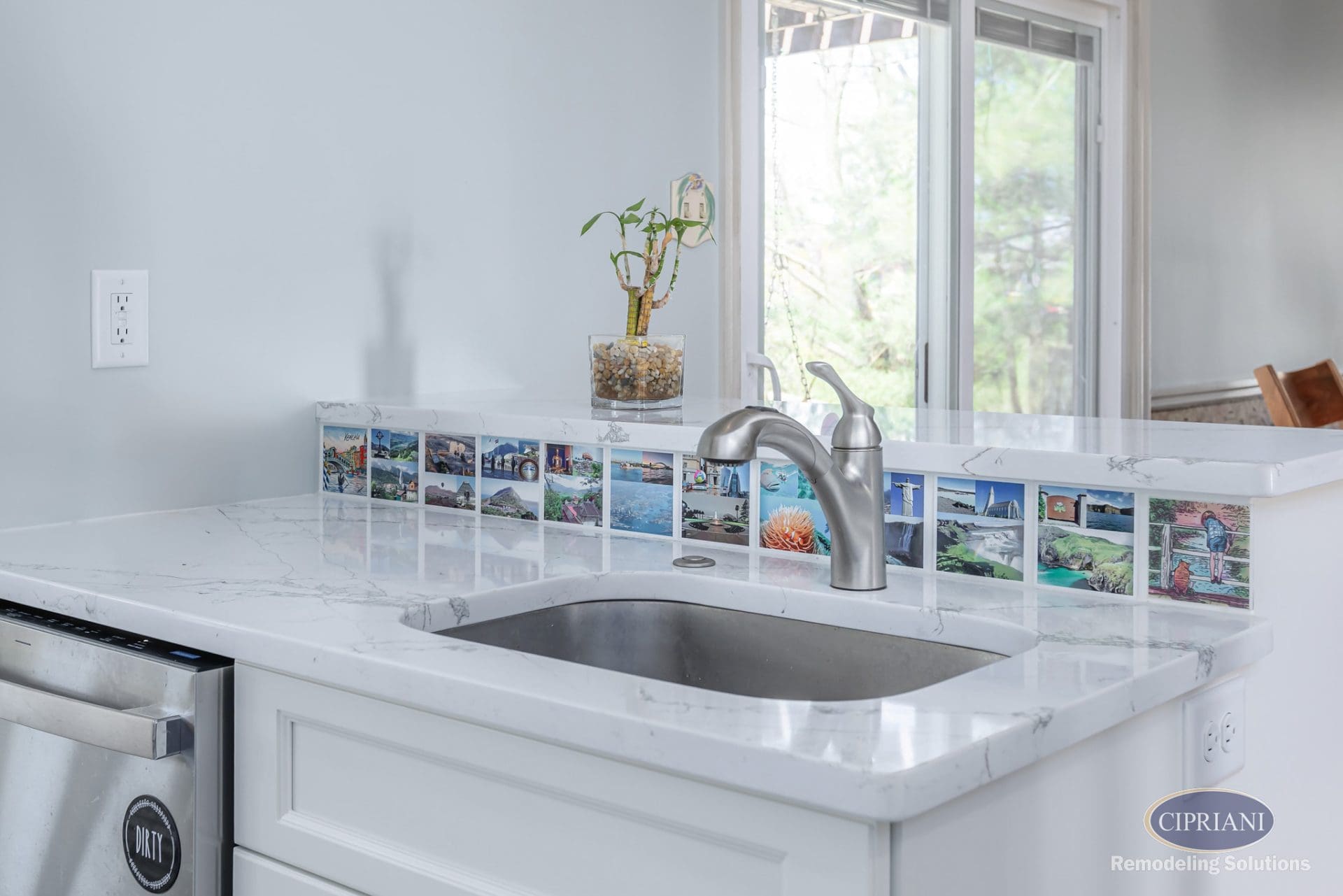 White marble kitchen peninsula with postcard tile backsplash and brushed nickel faucet.