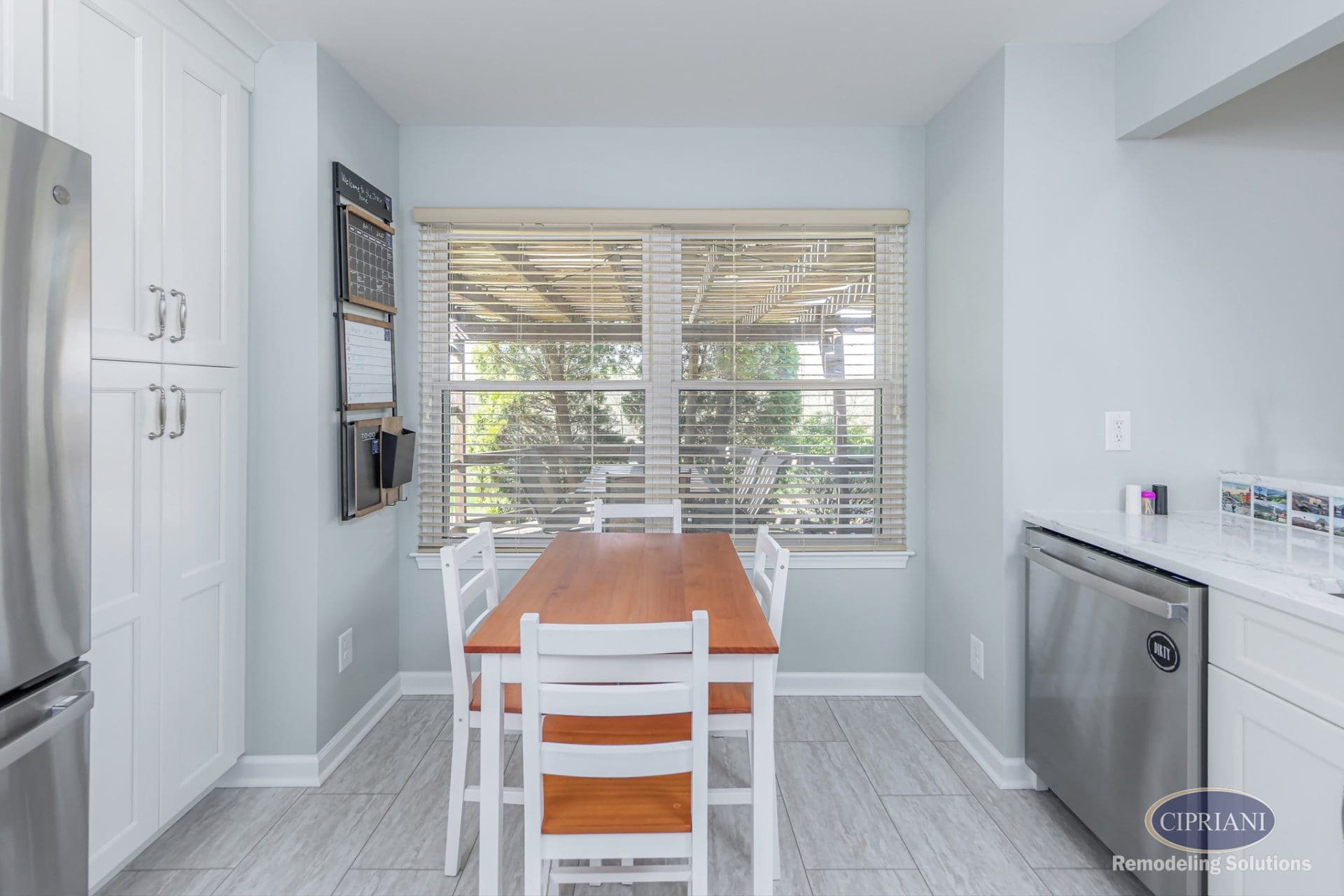 Cozy kitchen corner with wood dining table, large window, and stainless dishwasher.