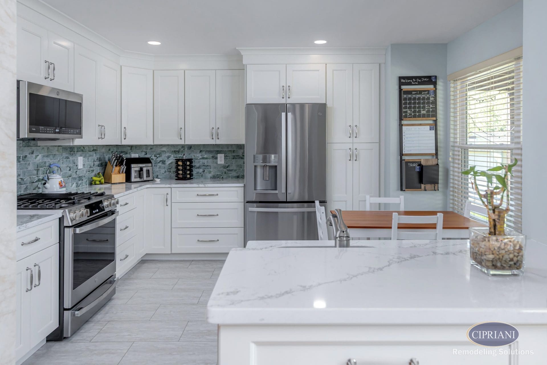 Wide view of kitchen from peninsula showing white cabinetry, stainless appliances, and dining nook.