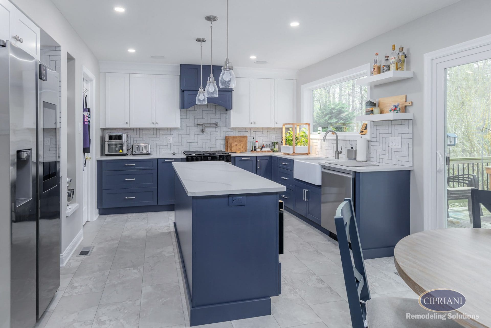 Transitional kitchen with navy island, white upper cabinets, herringbone backsplash, and sliding glass doors.