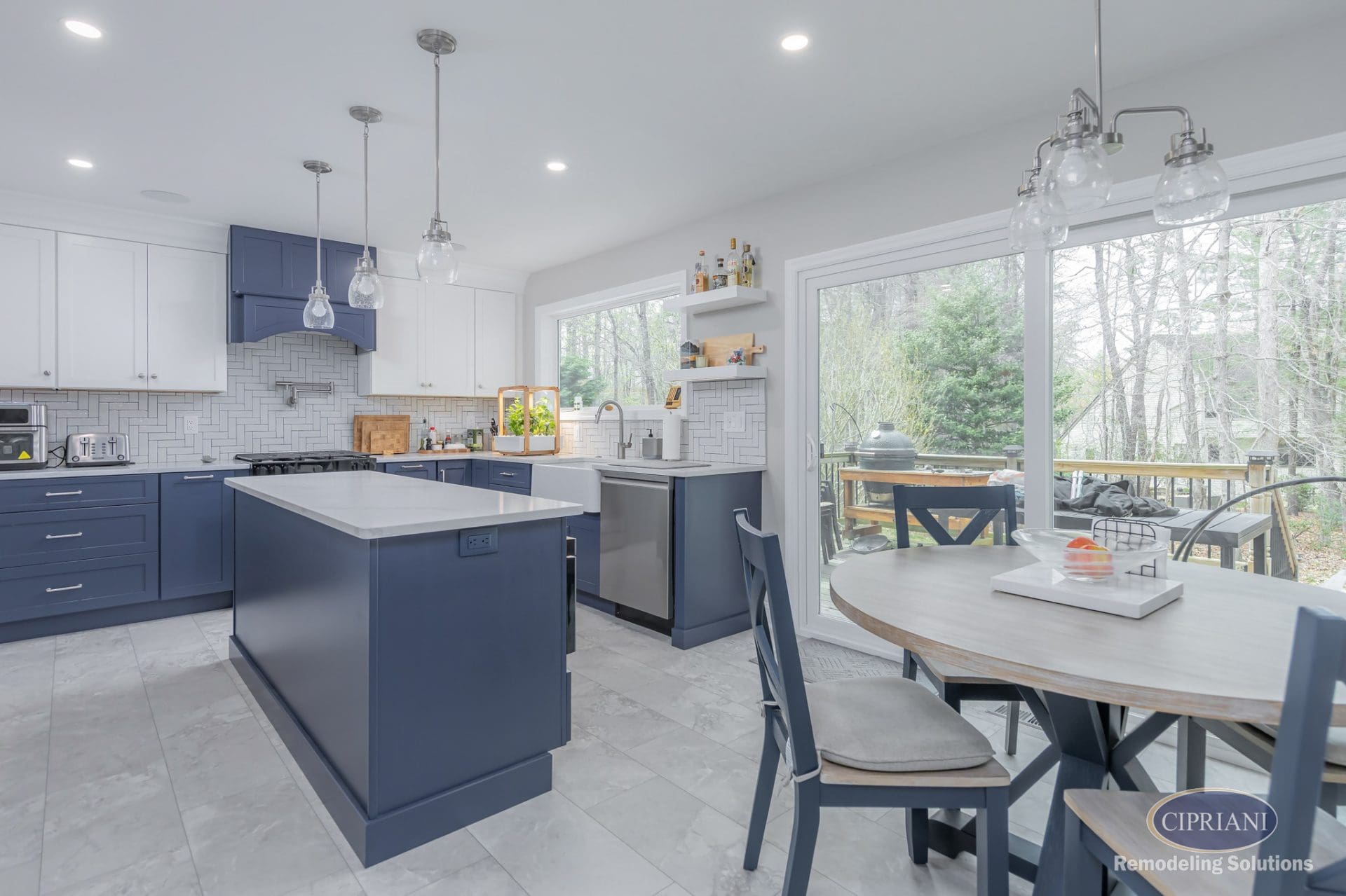 Transitional kitchen with navy island, white upper cabinets, herringbone backsplash, and sliding glass doors.