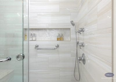 Shower wall with niche and fixtures – A close-up of the walk-in shower shows chrome fixtures, a handheld sprayer, and a recessed niche with decorative tile and built-in storage.