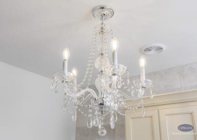 Crystal chandelier close-up – A glamorous crystal chandelier with hanging prisms and candle-style bulbs adds elegance to the bathroom ceiling.