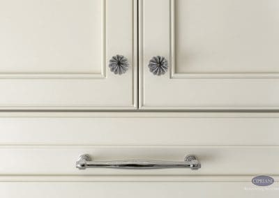 Cabinet hardware detail – A close-up of cream cabinetry showcasing decorative floral knobs and a polished chrome drawer pull.
