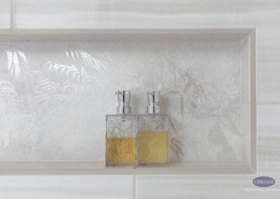 Shower niche with textured tile – A close-up of a recessed shower niche featuring leaf-patterned tile and two geometric soap dispensers.