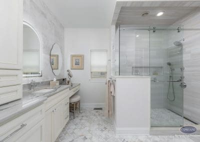 Bathroom vanity and shower – A wide-angle view of the bathroom reveals a built-in makeup vanity, arched mirror, and frameless glass shower with full tile surround.