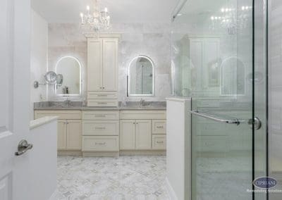 Bathroom entrance view – A full view from the doorway reveals a symmetrical double vanity with arched mirrors and a glass walk-in shower to the right.