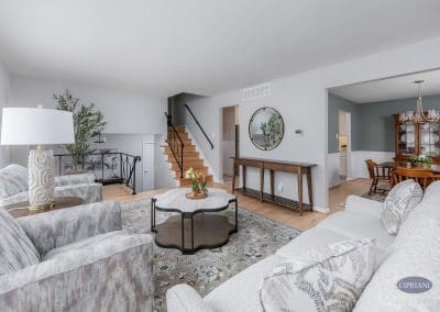 Open concept living room – A light and airy living room flows into the dining area, featuring new hardwood floors, updated paint, and stylish furnishings with warm wood accents.