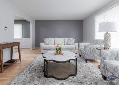 Neutral living room with accent wall – A bright, neutral living room features a soft gray sofa, sculptural coffee table, and a charcoal-gray accent wall for contrast.