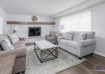 Bright Fireplace Living Room – A neutral-toned living room with a painted brick fireplace, soft furnishings, and natural light streaming through wide blinds.