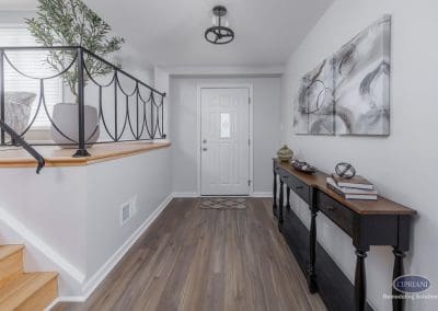 Inviting Entryway with Black Console Table – A bright foyer with light wood flooring, abstract wall art, and a black console table styled with books and decor.