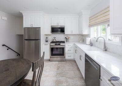 Bright White Kitchen Layout – A stylish kitchen with white cabinetry, stainless steel appliances, and soft Roman shades creating a clean, airy atmosphere.