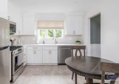 Bright White Kitchen with Dining Space – A cozy eat-in kitchen with white cabinetry, stainless steel appliances, and a warm wood dining table.