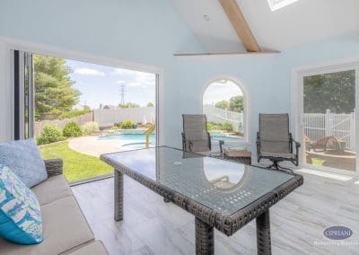 Indoor-outdoor sunroom with glass table and open poolside view