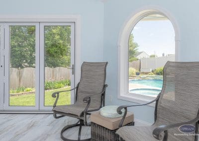 Cozy sunroom seating with arched window view of backyard pool