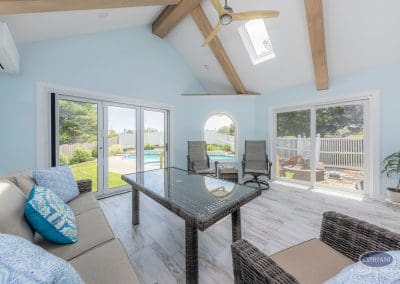 Bright sunroom with vaulted ceiling and poolside views