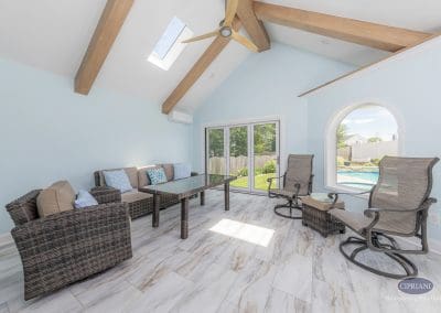 Interior view of sunroom with vaulted ceiling, wood beams, and backyard pool view