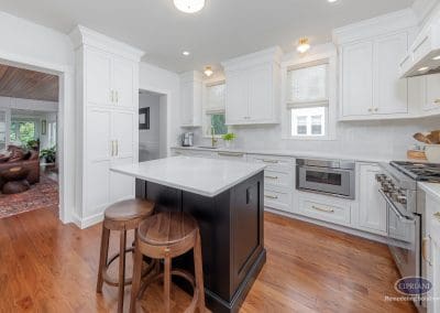 Bright white kitchen with black island and walnut stools
