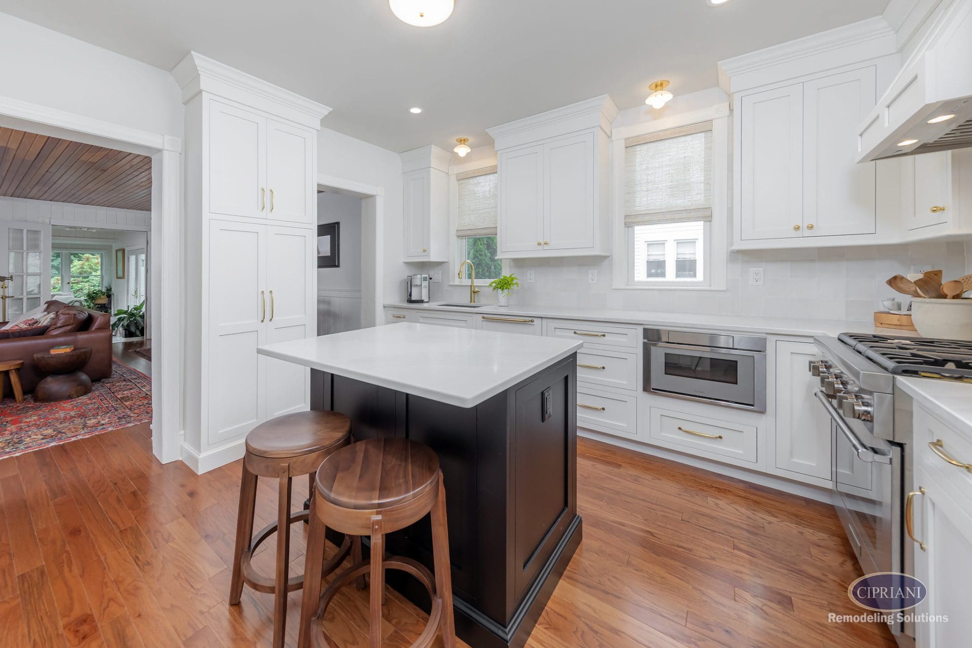 Bright white kitchen with black island and walnut stools