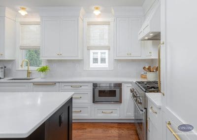 Bright white kitchen with gold hardware, stainless steel appliances, and a central island.