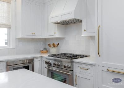 Bright kitchen corner with white cabinets, gold hardware, and stainless steel gas range.