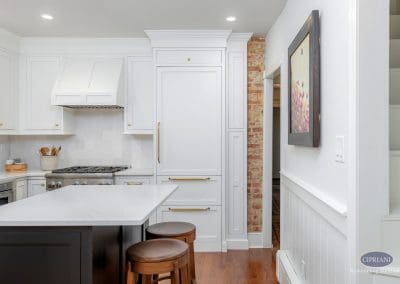 Bright kitchen with white cabinetry, a dark island, and exposed brick accent wall.
