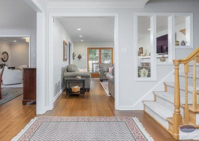 Bright hallway view leading into a cozy living room with French doors and leather seating.