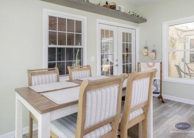 Modern dining nook with striped chairs and bright natural light in a Mount Laurel sunroom remodel.