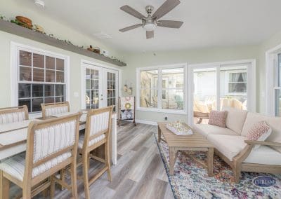 Bright sunroom with dining table, sofa, and ceiling fan for a cozy gathering space.