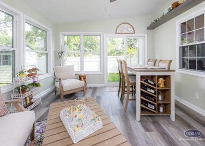 Bright sunroom with dining island, cozy seating, and decorative shelving.