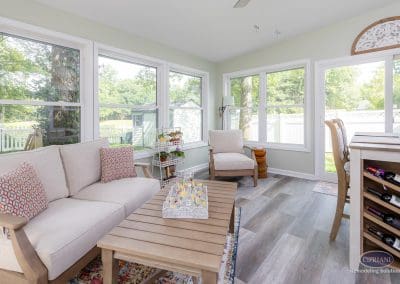 Mount Laurel sunroom remodel with sofa, armchair, and coffee table in a bright corner space.