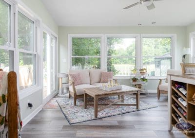 Mount Laurel sunroom remodel with loveseat, coffee table, and garden views through large windows.
