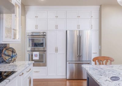 Wall of white cabinetry with built-in double ovens and French door refrigerator.