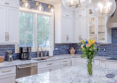 Elegant kitchen sink view with white cabinets and gold faucet.