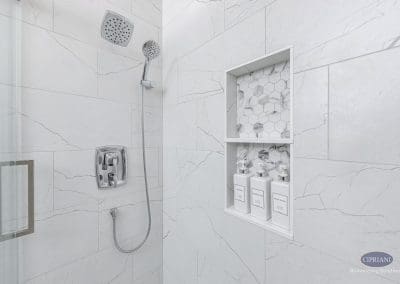 Modern shower with chrome fixtures – A glass-enclosed shower featuring chrome fixtures and a built-in niche with marble hexagon tile.