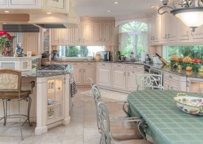 Elegant kitchen with breakfast table and detailed cabinetry. The soft cream finishes and granite countertops create a timeless, welcoming atmosphere.