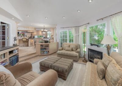 Warm, open-concept living area with view into classic kitchen. A cozy sitting room with neutral furnishings connects seamlessly to the bright kitchen, creating an inviting flow of light and comfort.