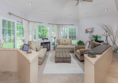 Spacious sitting room with neutral décor and large windows. The cathedral ceiling and surrounding greenery create an open, relaxing atmosphere.