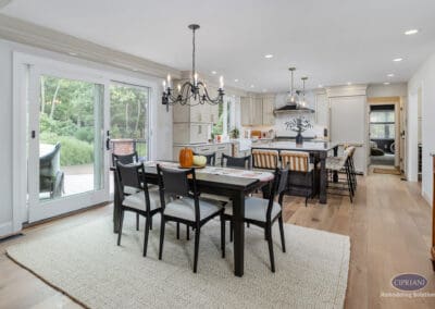 Open kitchen and dining layout A wide view of an open kitchen and dining space with a large island, pendant lighting, wide-plank hardwood floors, and sliding glass doors leading outdoors.